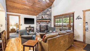 Una sala de estar acogedora con chimenea de piedra, techo de madera y un sofá cómodo.