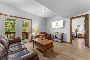 Een woonkamer met een leren bank, een houten salontafel en een aan de muur bevestigde televisie.