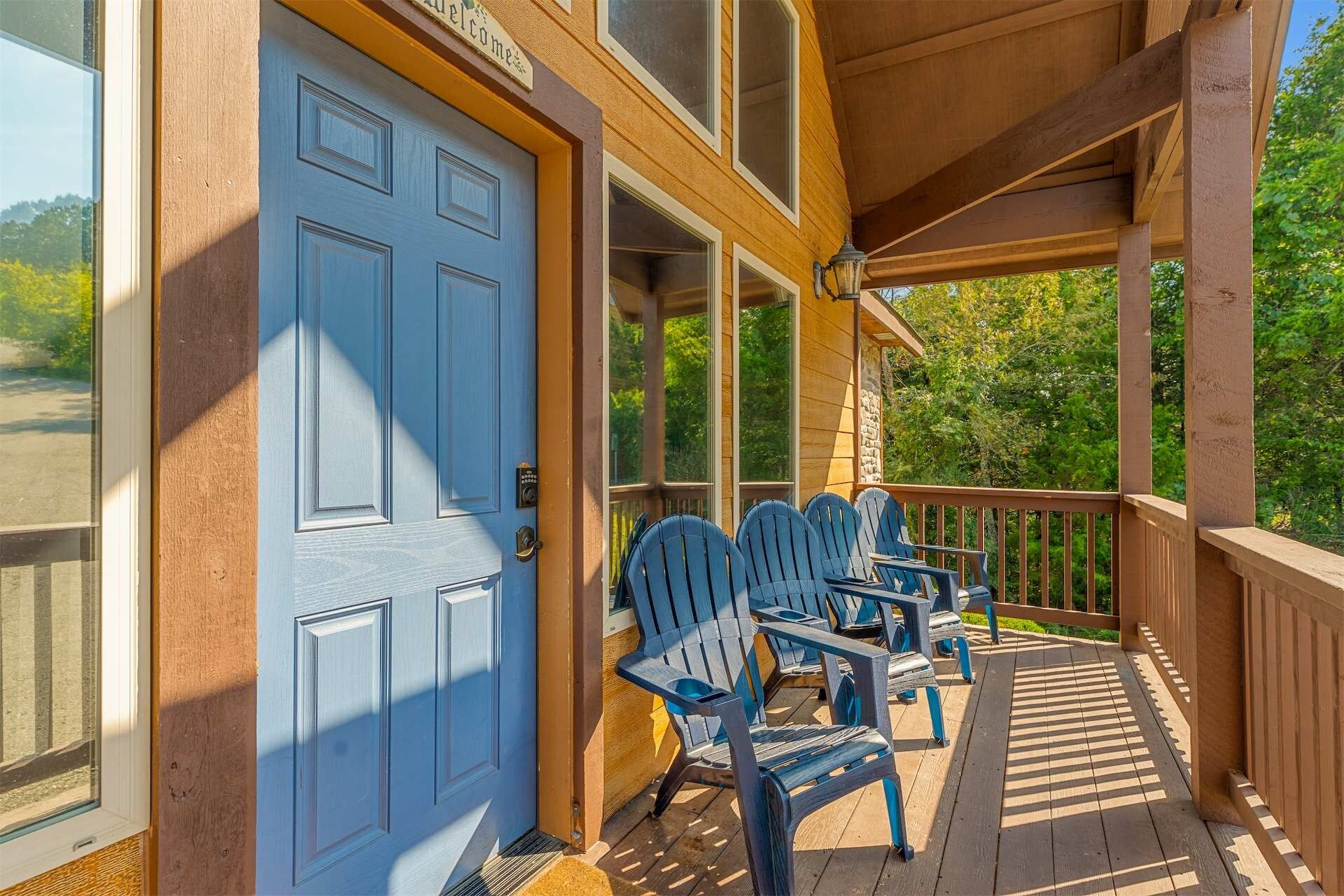 Un porche de madera con sillas Adirondack y una puerta azul.