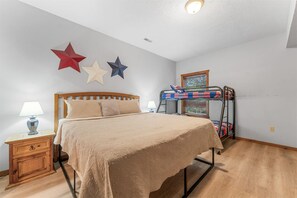 Une chambre à coucher avec un lit, une table de chevet, une lampe, un lit superposé et des éléments décoratifs sur les murs.