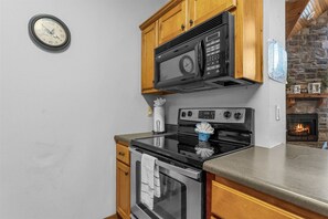 Een keuken met een magnetron, oven en een klok aan de muur.