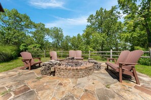 Une terrasse en pierre avec un foyer et des fauteuils Adirondack.