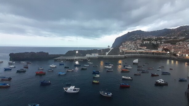 A coastal town with boats docked along the harbor, a prominent cliff, and buildings on the hillside. - Villa Supranee relaxation a unforgettable stay, brand new  accommodation 850sft. (camara de lobos)