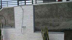 A shower area with a wall-mounted showerhead, a potted plant, and a concrete ledge. - Villa Supranee relaxation a unforgettable stay, brand new  accommodation 850sft. (camara de lobos)