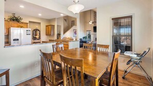 A spacious dining area with a wooden table and chairs, a kitchen with wooden cabinets, and a ceiling fan. - Rest Nest in the Heart of Ozark's Nature! (Branson West)