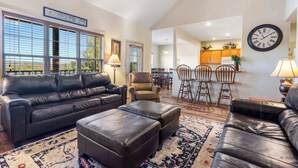A spacious living room with a leather sofa, ottoman, and a dining area with wooden chairs and a table. - Rest Nest in the Heart of Ozark's Nature! (Branson West)