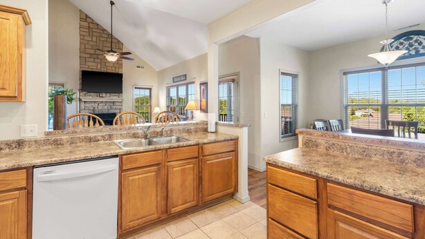 A spacious kitchen with granite countertops, wooden cabinets, and a built-in dishwasher. - Rest Nest in the Heart of Ozark's Nature! (Branson West)