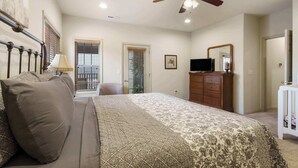 A bedroom with a bed, a ceiling fan, a dresser, a television, and a door leading to another room. - Rest Nest in the Heart of Ozark's Nature! (Branson West)