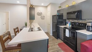 A modern kitchen with a central island, stainless steel appliances, and a red rug. - Holiday Ridge Escape | Holiday Hills Branson | Golf Resort | Outdoor pools (Branson)