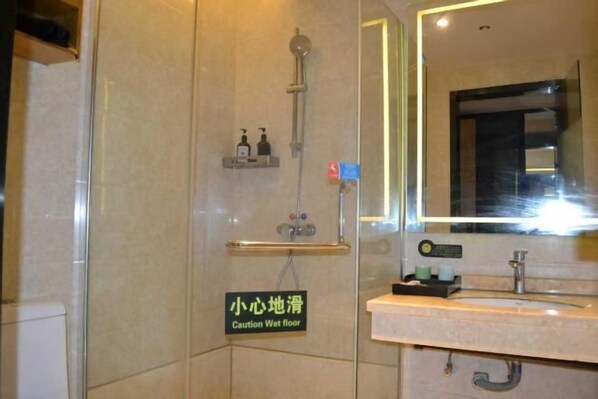 Une salle de bain avec un panneau d’avertissement indiquant « sol glissant », une douche, un lavabo avec un miroir et des articles de toilette accrochés au mur.
