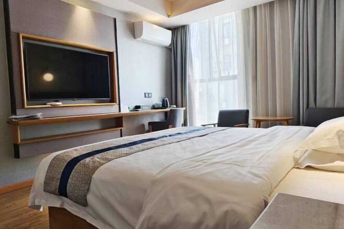 A hotel room with a bed, a TV, a desk, and a chair.