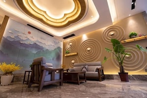 Un vestíbulo moderno con un mural, un sofá, una silla y una planta en maceta.