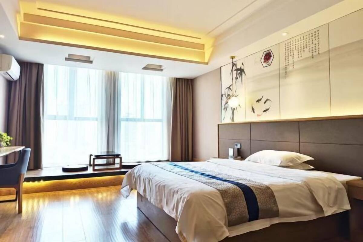 A modern hotel room with a large bed, a desk, and a view of the city.