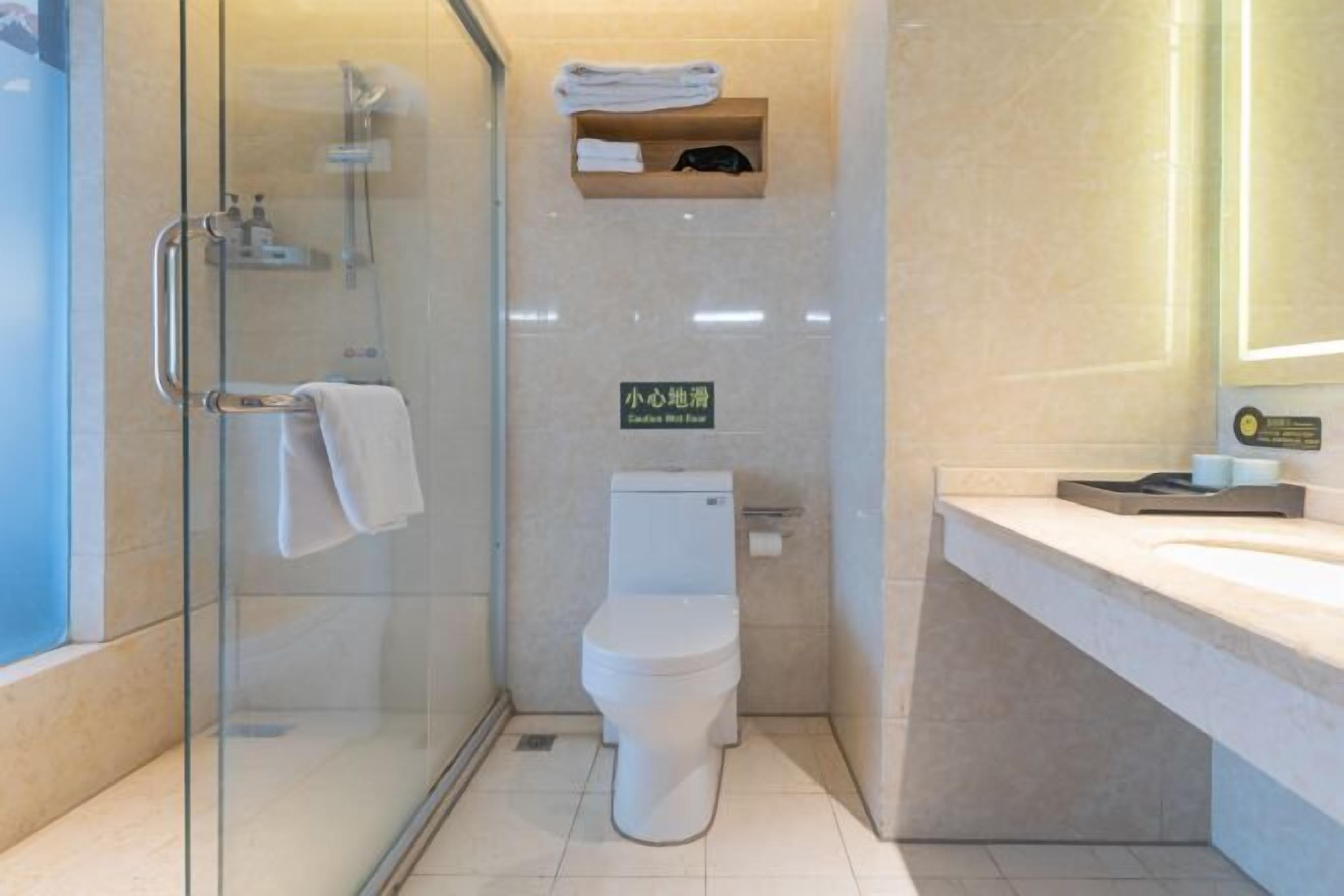 Une salle de bain moderne avec une douche à parois de verre, des toilettes, un lavabo et un porte-serviettes.
