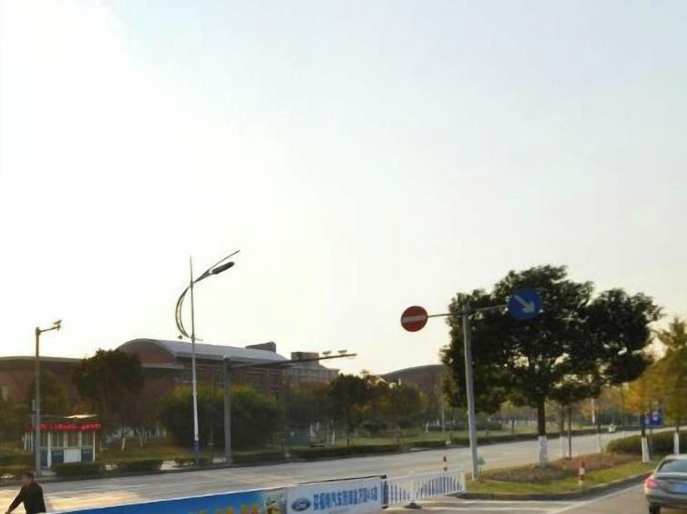 A road with a no entry sign, a blue directional sign, and a pedestrian crossing.