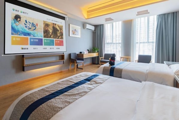 A hotel room with two beds, a desk, a chair, a TV screen, and large windows.