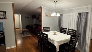 Comedor con una mesa dispuesta para cuatro personas, sillas, dispensador de agua y refrigerador.