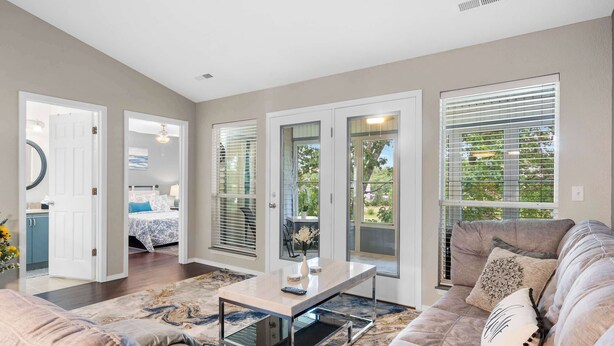 A modern living room with a sofa, a coffee table, and a view of a bedroom through a glass door. - Linda’s Haven – Golf Course View (Branson)