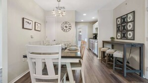 A dining area with a wooden table and chairs, a chandelier, and framed pictures on the wall. - Hillside Cottage in The Vineyards Resort! (Branson)