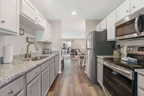 A modern kitchen with granite countertops, stainless steel appliances, and light-colored cabinetry.