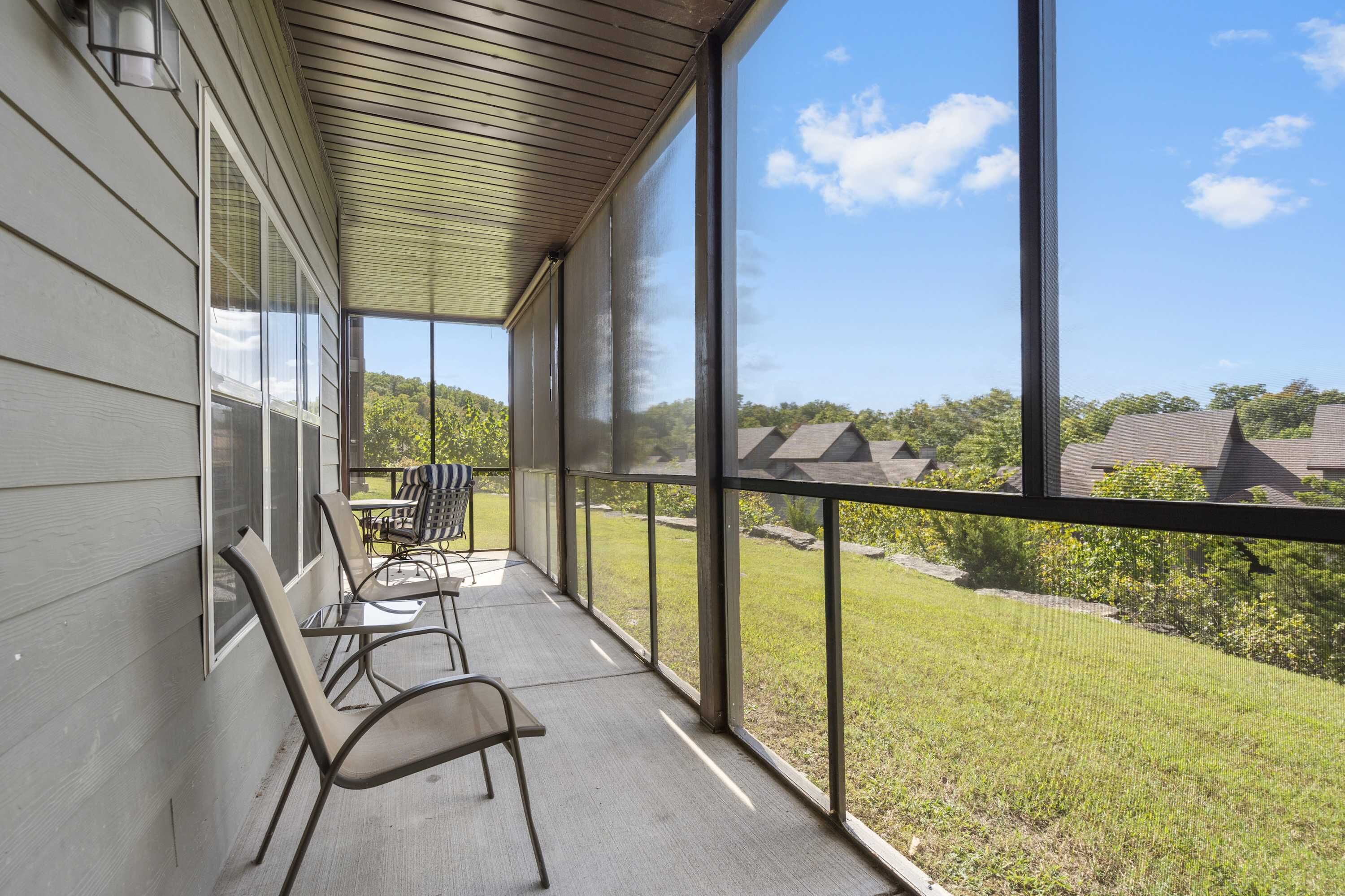 A covered porch with a view of a grassy yard and neighboring houses.