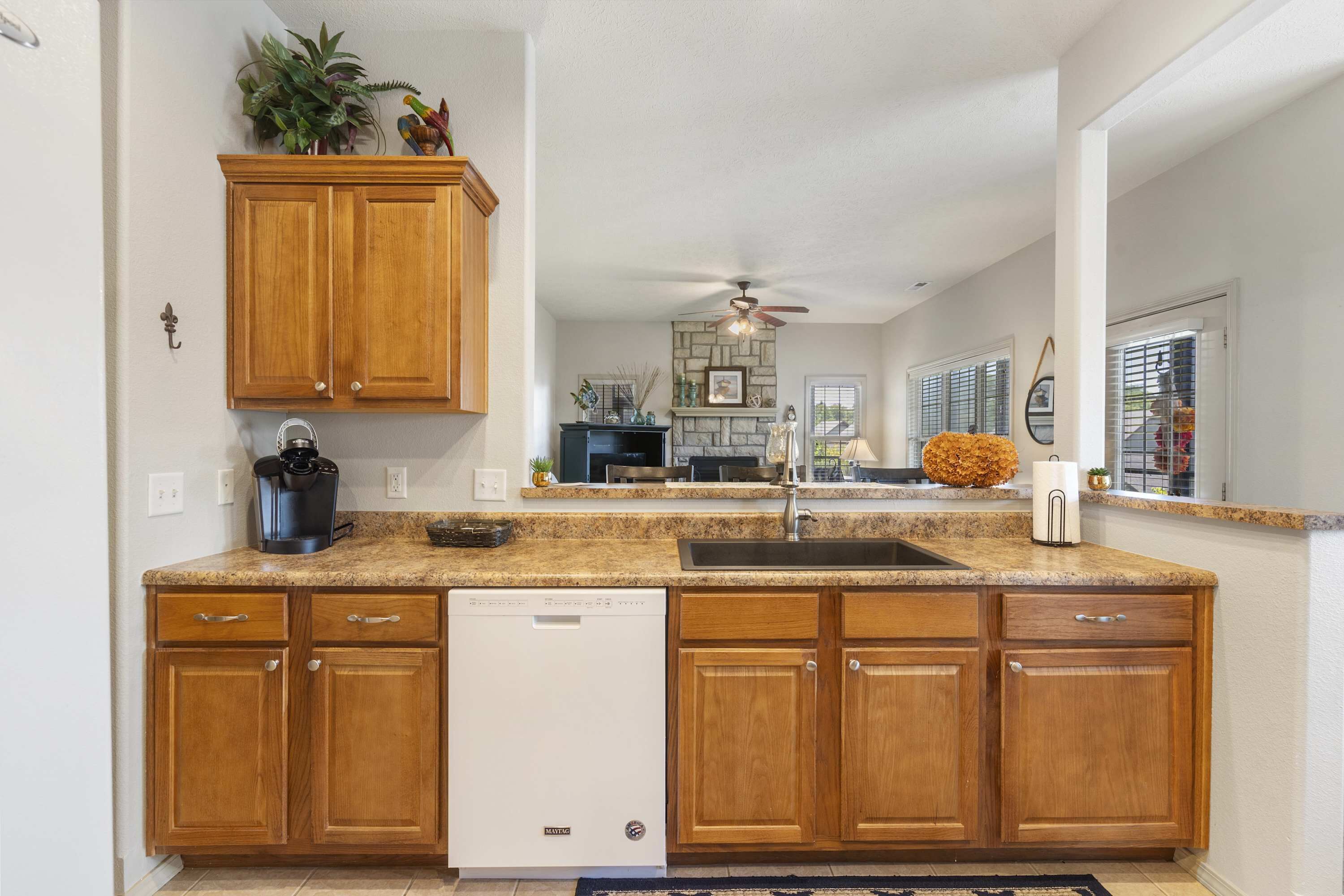A kitchen with wooden cabinets, a dishwasher, granite countertops, and a ceiling fan.