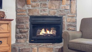 A stone fireplace with a black screen, a wooden mantel, and a woven basket on the left. - Milby Hideaway w/ On-site Amenities (Branson West)