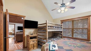 A room with a bunk bed, a ceiling fan, a television, and a window with blinds. - Milby Hideaway w/ On-site Amenities (Branson West)