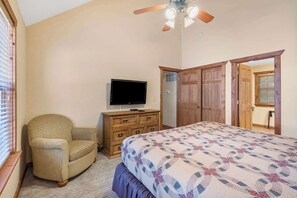 Een slaapkamer met een bed, een televisie op een dressoir, een stoel en een kledingkast.