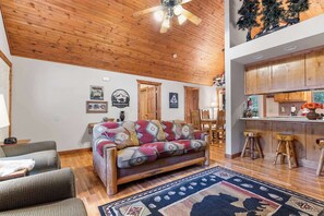 Un salon chaleureux avec un plafond en bois, un canapé à motifs et un tapis.