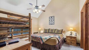 Ein Schlafzimmer mit Etagenbett, Schreibtisch inklusive Tastatur, Lampe und Deckenventilator.