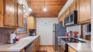 A compact kitchen with wooden cabinets, a stainless steel refrigerator, and a microwave. - Milby Hideaway w/ On-site Amenities (Branson West)