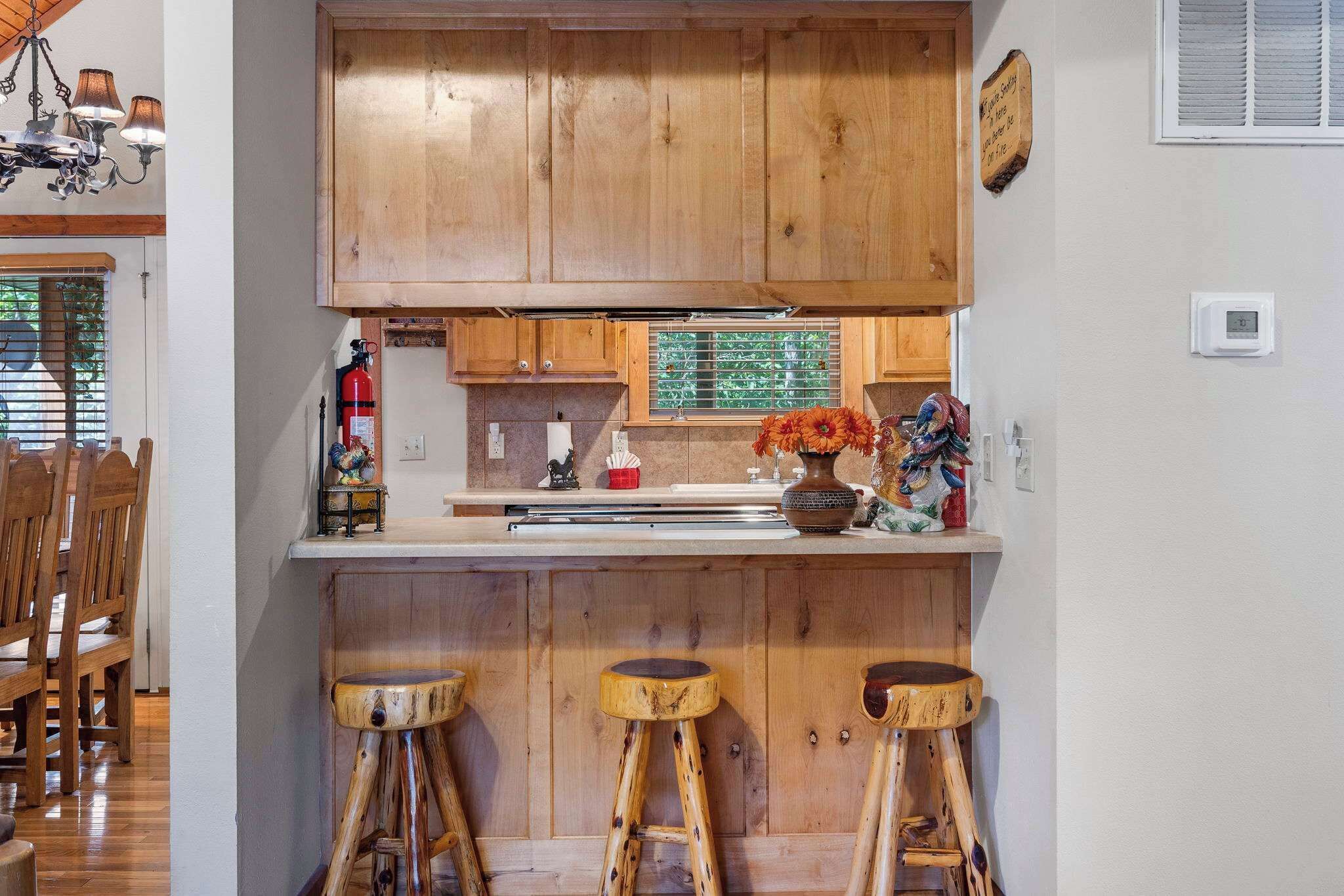 A kitchen with wooden cabinets, a bar area with stools, and a fire extinguisher.