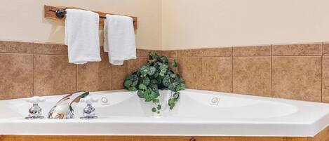 A bathroom with a bathtub, wooden cabinets, and a potted plant.