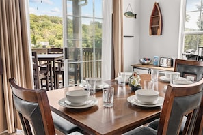 A dining area with a wooden table set for four, surrounded by chairs. - Peaceful Lakeview Escape - For 6 (Branson)