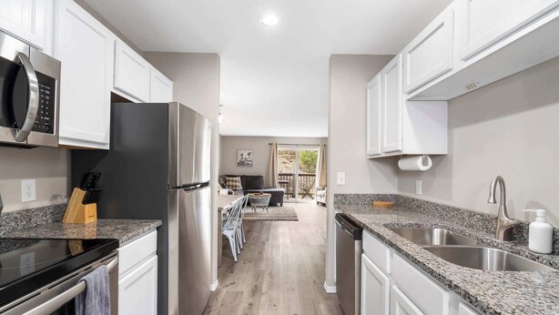 A modern kitchen with white cabinets, stainless steel appliances, granite countertops, and a central island.