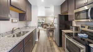 Una cocina moderna con encimeras de granito, electrodomésticos de acero inoxidable y armarios de madera oscura.