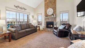 A spacious living room with a fireplace, a large window, and a stone accent wall.