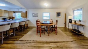 A spacious kitchen with a dining area, wooden flooring, and a large window providing natural light. - Cave Run Lodge Near Lake & Marina Cabin Suite #8 (Morehead)