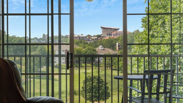 Un balcon donnant sur un terrain de golf, un bâtiment visible au loin et une chaise.