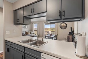 A kitchen with dark cabinets, a double sink, and a dining area with a view. - Luxurious Golf Front; Home for 4 (Branson)