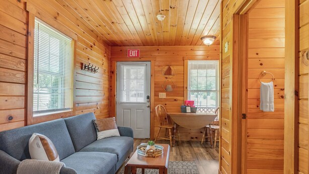 L’intérieur chaleureux d’un chalet avec un canapé, une table à manger et un coin cuisine.