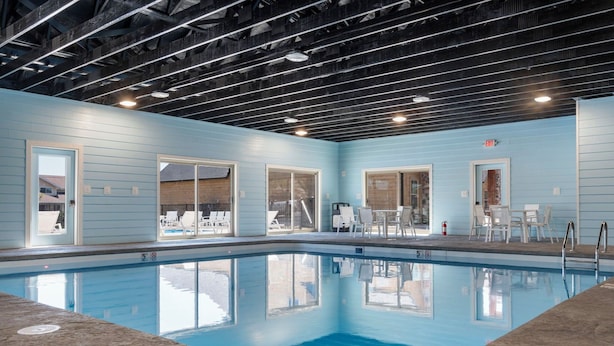 An indoor swimming pool with clear blue water, surrounded by light blue walls and white doors. - Two Pines – Endless Views and Attractions! (Branson)