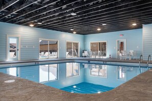 An indoor swimming pool with clear blue water, surrounded by light blue walls and white doors. - Two Pines – Endless Views and Attractions! (Branson)