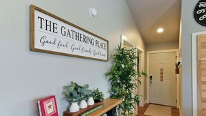 Een hal met een bord waarop 'THE GATHERING PLACE' staat, een plank met planten en een rood notitieboek.