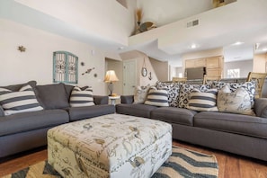 A living room with a grey sofa set, patterned ottoman, and decorative wall art. - Garden View Escape | Resort Amenities (Branson)