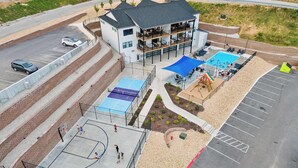 A multi-story building with a rooftop pool, a basketball court, and a playground area. - Hilltop Haven at Table Rock – Lake Views & Nearby Branson’s Best Attractions (Branson)