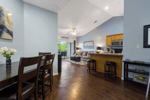 A modern kitchen with a bar area, wooden dining table, and chairs.
