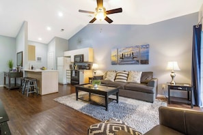 A modern living room with a sofa, coffee table, and a dining area with a kitchen in the background. - Holiday Ridge Retreat Duo Holiday Hills Branson Golf Resort  Outdoor Pools (Branson)