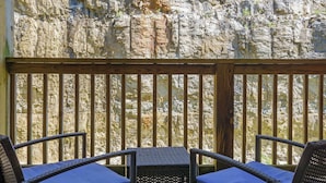 A wooden deck with wicker chairs and a table, overlooking a rocky cliff. - Hillside Duo | 2 Units in The Vineyards Resort (Branson)
